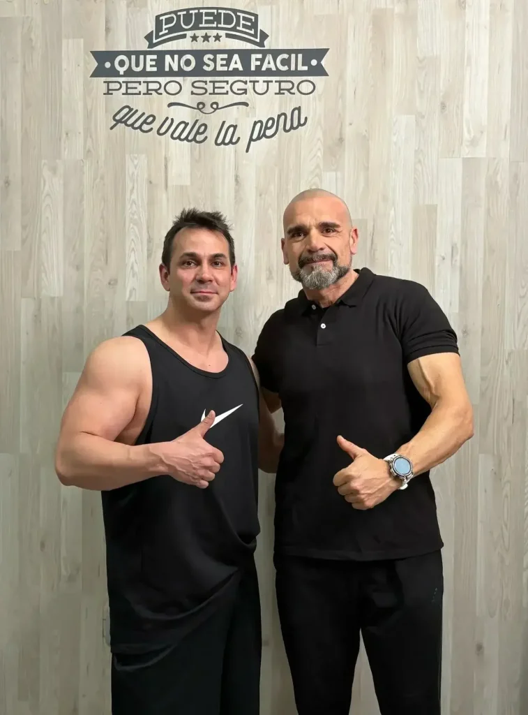 Víctor Espejo, cliente de Personal Fit Sevilla, posando junto al entrenador Jose en el gimnasio tras su transformación física.